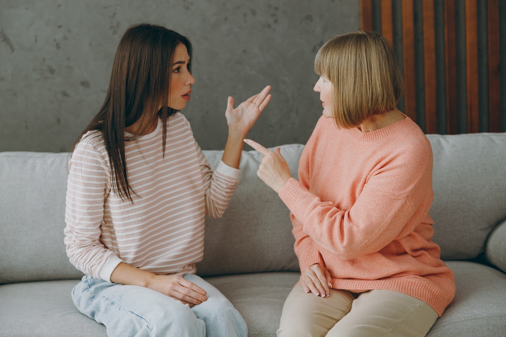 Young adult woman arguing or fighting with her mother on a couch