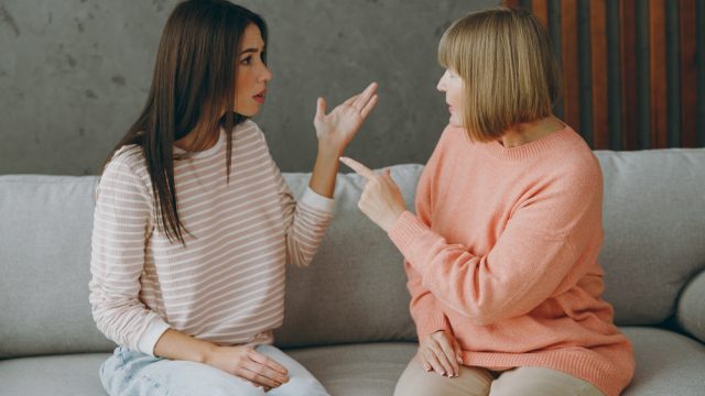 Young adult woman arguing or fighting with her mother on a couch