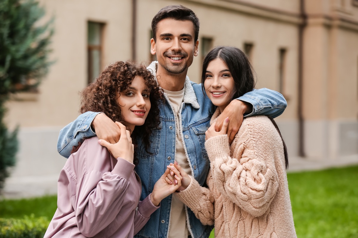 Man with two beautiful women outdoors. Polyamory concept