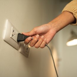 Close up woman hand put on or remove Electric plug cable in socket. Electrical equipment wires and power strips on the wall. Earth Hour saving energy.