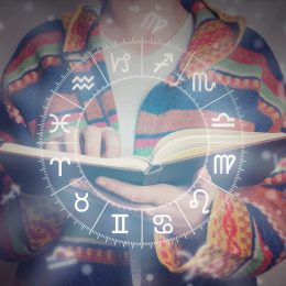 person reading an astrology book with zodiac graph imposed over photo