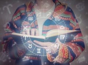 person reading an astrology book with zodiac graph imposed over photo
