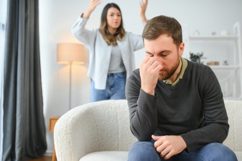 Family quarrel, man and woman sitting on sofa at home. angry woman yells at her husband.