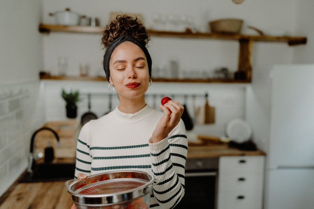 A young woman eating strawberries in the kitchen