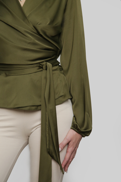 cropped image of a woman wearing a green wrap shirt and beige pants