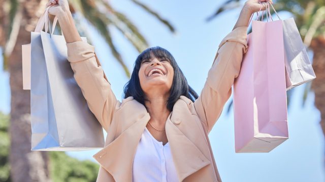 A woman holding up shopping bags with a happy look on her face