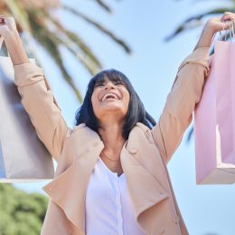 A woman holding up shopping bags with a happy look on her face