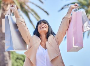 A woman holding up shopping bags with a happy look on her face