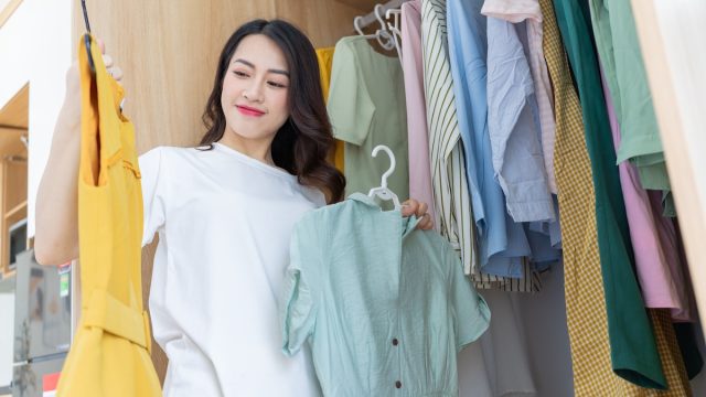 Woman in closet looking at pastel colored clothes