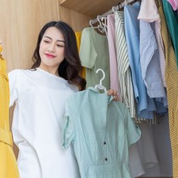 woman in closet looking at two items of clothing