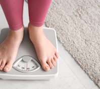 closeup of a young woman in pink leggings standing on a scale