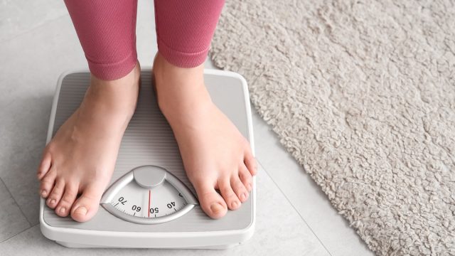 closeup of a young woman in pink leggings standing on a scale
