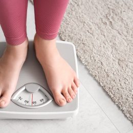 closeup of a young woman in pink leggings standing on a scale
