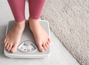 closeup of a young woman in pink leggings standing on a scale