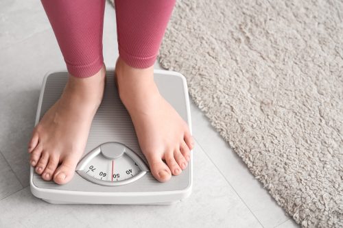 closeup of a young woman in pink leggings standing on a scale