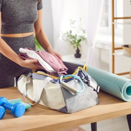 Close up shot of a woman hands packing sports bag with sportswear and equipment