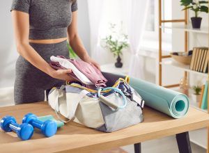 Close up shot of a woman hands packing sports bag with sportswear and equipment