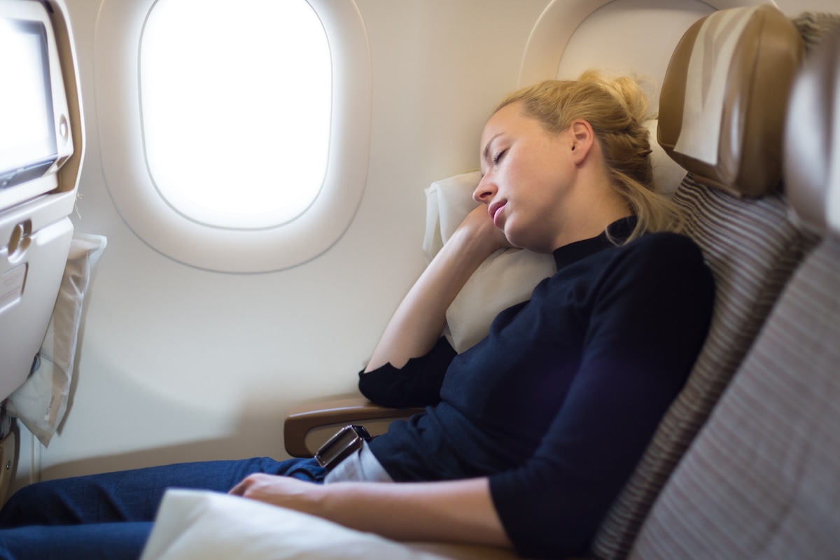 woman in a window seat sleeping on a plane
