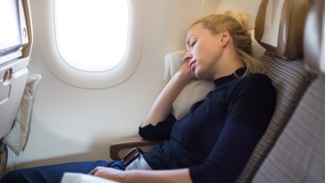 woman in a window seat sleeping on a plane