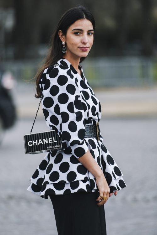 Bettina Looney wearing a black-and-white polka dot peplum top, carrying a Chanel bag
