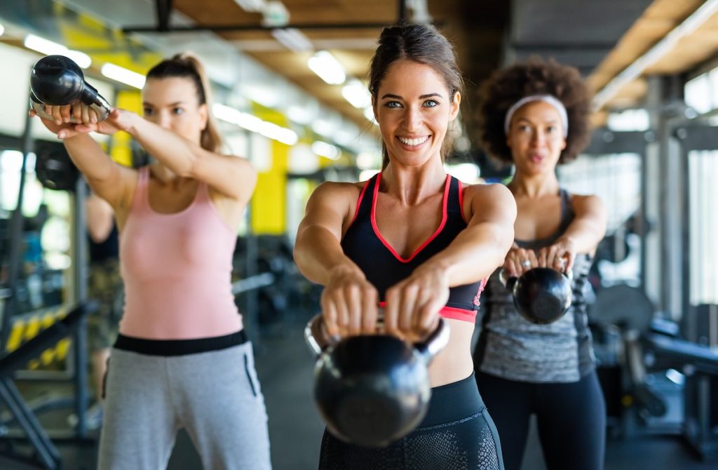 Three women doing a kettlebell workout at the gym