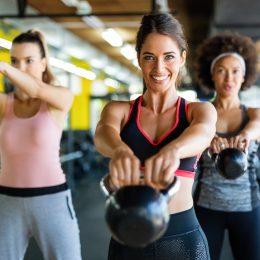 Three women doing a kettlebell workout at the gym