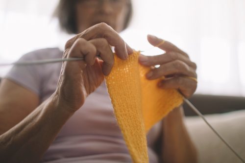 Cropped shot of woman knitting with a yellow wool