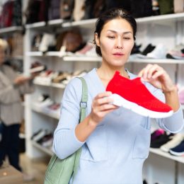 Woman looking at red slip-on sneakers in the shoe store