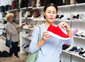 Woman looking at red slip-on sneakers in the shoe store