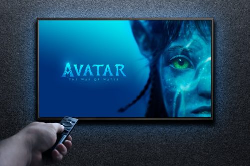 Man turns on TV with remote control. TV screen playing Avatar the way of water trailer or movie. Moscow, Russia - December 14, 2022.