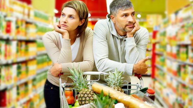 Image of forlorn-looking couple with cart in supermarket