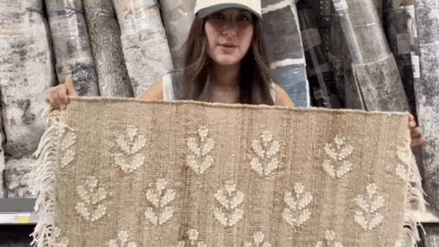 Shopper holding up a jute rug at Walmart