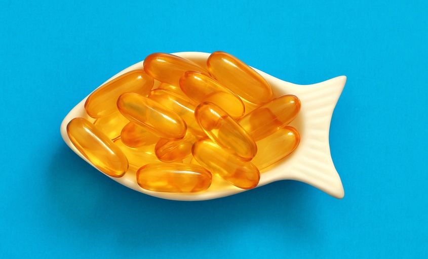 fish oil capsules in a fish-shaped bowl on a blue background