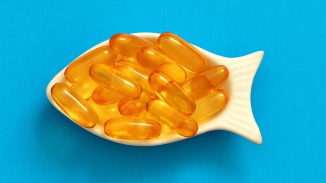 fish oil capsules in a fish-shaped bowl on a blue background