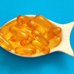 fish oil capsules in a fish-shaped bowl on a blue background