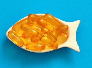 fish oil capsules in a fish-shaped bowl on a blue background