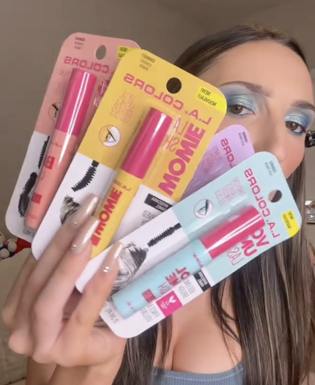 Woman holding up four L.A. Colors mascaras from Dollar Tree