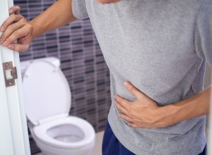 Man with a stomach ache holding the bathroom door and clutching his stomach