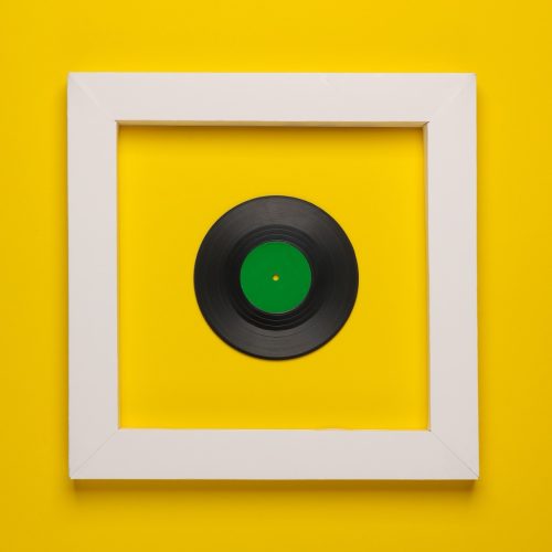 Vinyl record in white frame on yellow background.