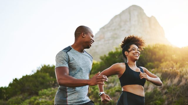 Sports, workout and couple walking by a mountain training for a race, marathon or competition. Fitness, nature and athletes doing an outdoor cardio exercise for health, energy and endurance at sunset