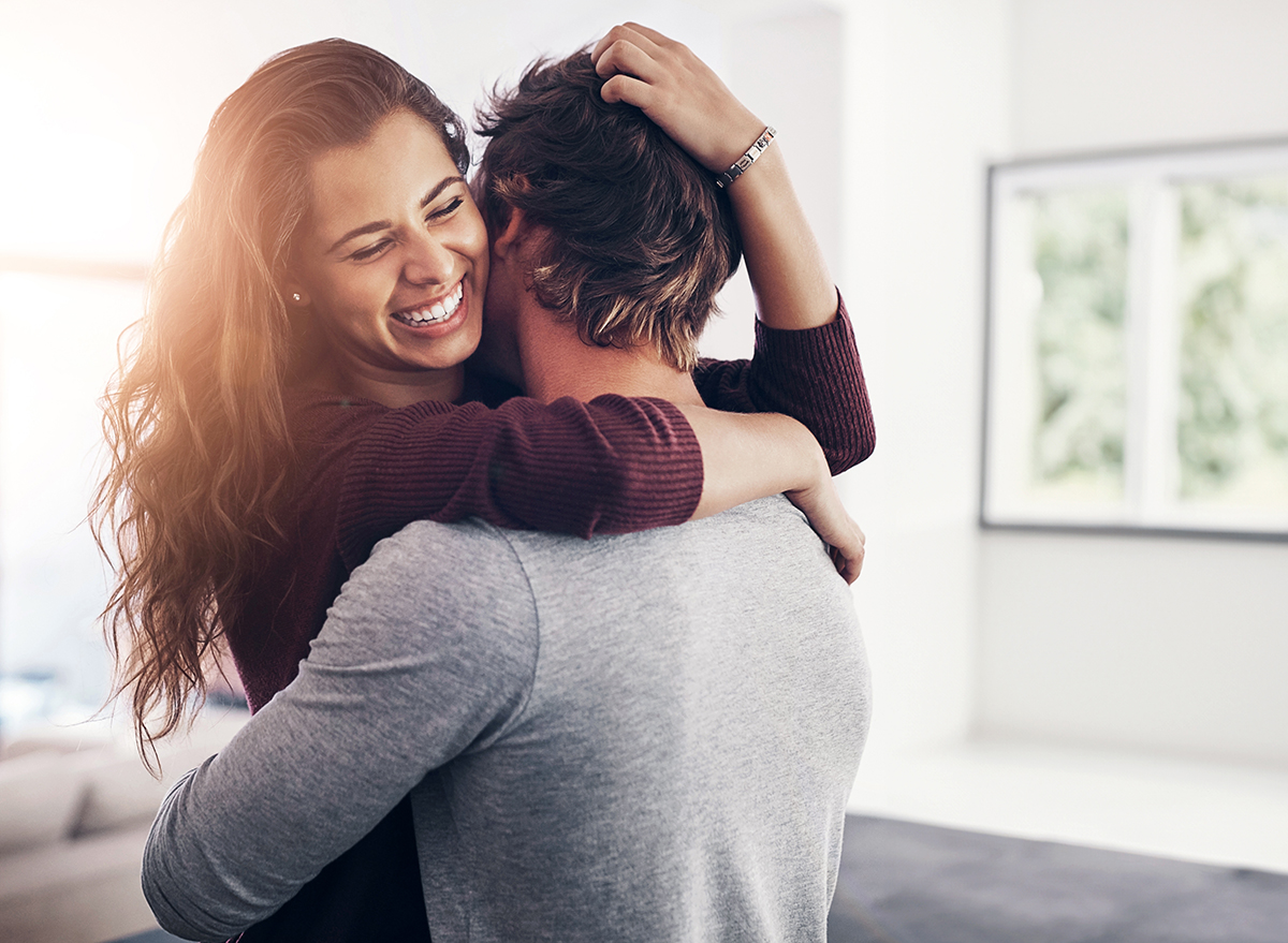 Couple, woman hug and laughing in home kitchen with love, bonding and smile together with joy. Embrace, romance and happy people with marriage with care, trust and commitment in house with fun joke