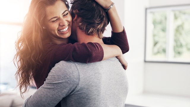 Couple, woman hug and laughing in home kitchen with love, bonding and smile together with joy. Embrace, romance and happy people with marriage with care, trust and commitment in house with fun joke