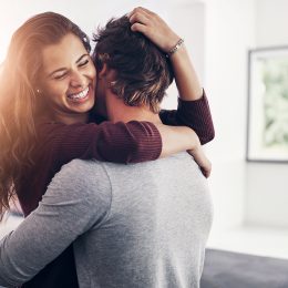 Couple, woman hug and laughing in home kitchen with love, bonding and smile together with joy. Embrace, romance and happy people with marriage with care, trust and commitment in house with fun joke