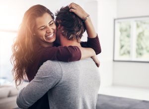 Couple, woman hug and laughing in home kitchen with love, bonding and smile together with joy. Embrace, romance and happy people with marriage with care, trust and commitment in house with fun joke