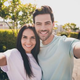 Photo of lovers couple take selfie look camera toothy shiny smile wear casual clothes in garden park outdoors