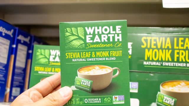 A view of a hand holding a package of Whole Earth Sweetener Company Stevia Leaf and Monk Fruit Natural Sweetener Blend at a local grocery store.