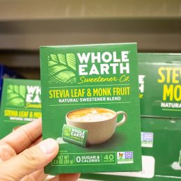 A view of a hand holding a package of Whole Earth Sweetener Company Stevia Leaf and Monk Fruit Natural Sweetener Blend at a local grocery store.