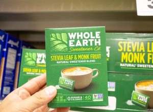 A view of a hand holding a package of Whole Earth Sweetener Company Stevia Leaf and Monk Fruit Natural Sweetener Blend at a local grocery store.
