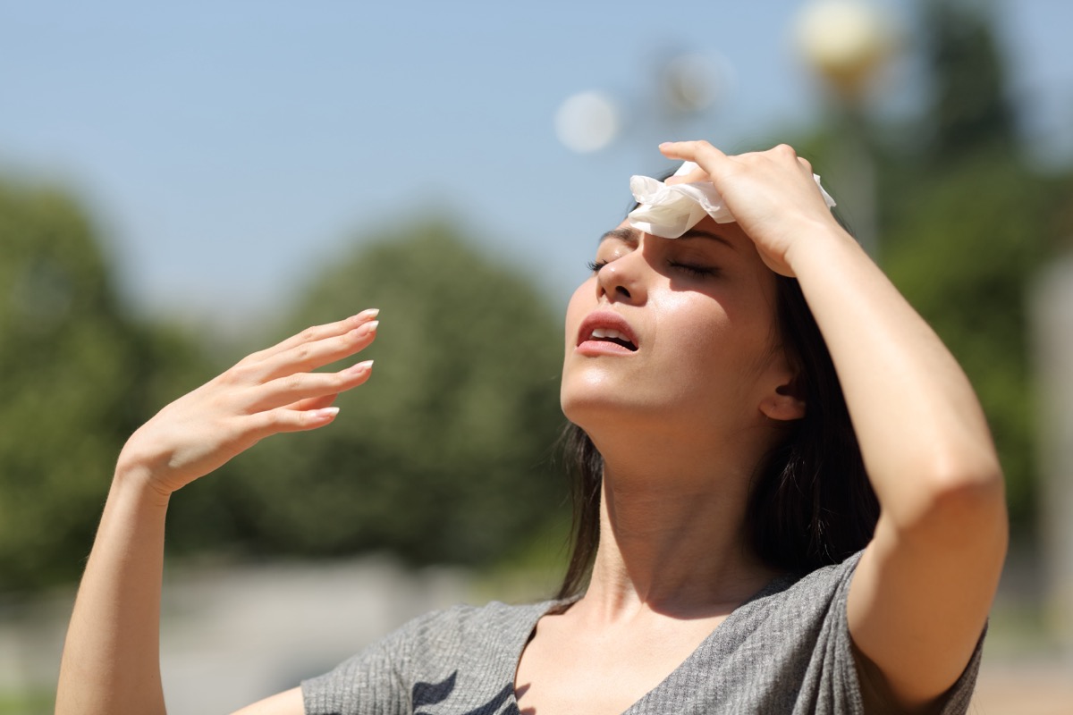 Stressed woman drying sweat with a cloth in a warm summer day.