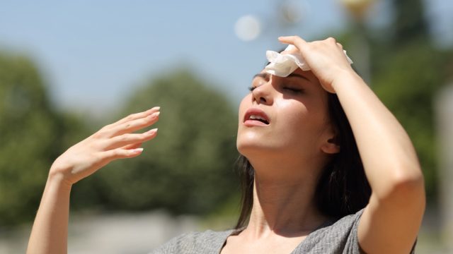 Stressed woman drying sweat with a cloth in a warm summer day.